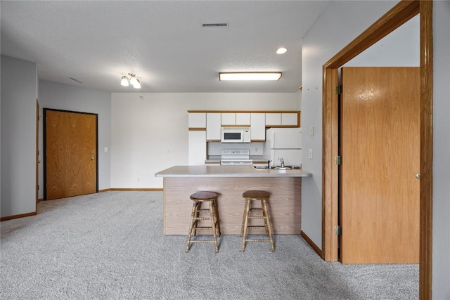 250 Cimarron Dr NE, Hiawatha, IA 52233 - kitchen with white appliances, light colored carpet, white cabinets, a breakfast bar area, and a peninsula