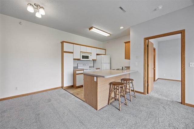 250 Cimarron Dr NE, Hiawatha, IA 52233 - kitchen with white appliances, light carpet, a kitchen breakfast bar, a peninsula, and recessed lighting