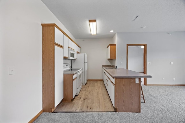 250 Cimarron Dr NE, Hiawatha, IA 52233 - kitchen featuring white appliances, a peninsula, a breakfast bar, white cabinets, and light colored carpet