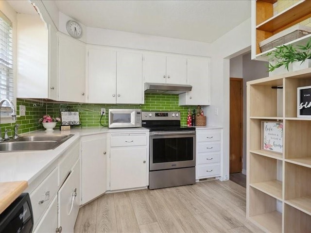 8 25th Ave SW, Cedar Rapids, IA 52404 - kitchen with electric stove, white microwave, under cabinet range hood, light countertops, and decorative backsplash