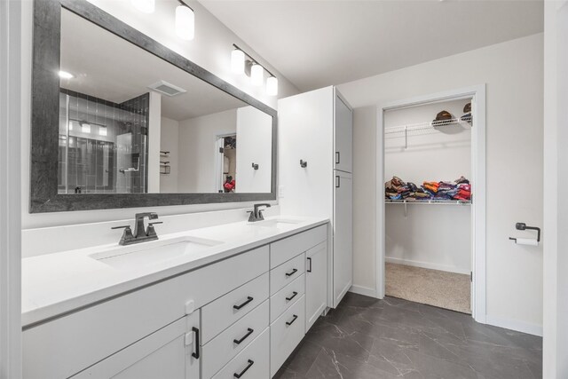 4263 Calder Dr, Marion, IA 52302 - bathroom featuring marble look tiles, double vanity, a walk in closet, and a tile shower