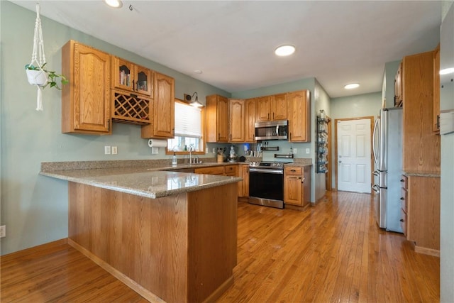 765 34th Ave, Marion, IA 52302 - kitchen with appliances with stainless steel finishes, a peninsula, light wood finished floors, glass insert cabinets, and recessed lighting
