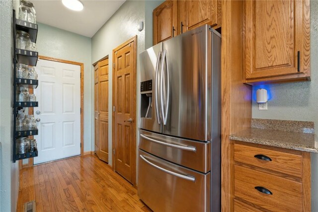 765 34th Ave, Marion, IA 52302 - kitchen featuring stainless steel refrigerator with ice dispenser, brown cabinetry, light wood-type flooring, light stone countertops, and a textured wall