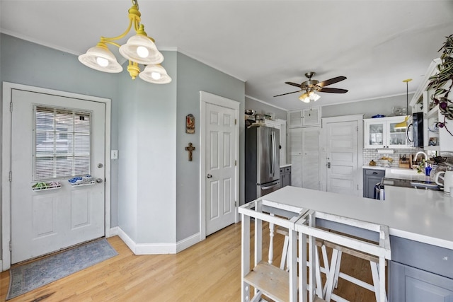 1812 Blake Blvd SE, Cedar Rapids, IA 52403 - kitchen featuring light wood-type flooring, a peninsula, a ceiling fan, crown molding, and glass insert cabinets