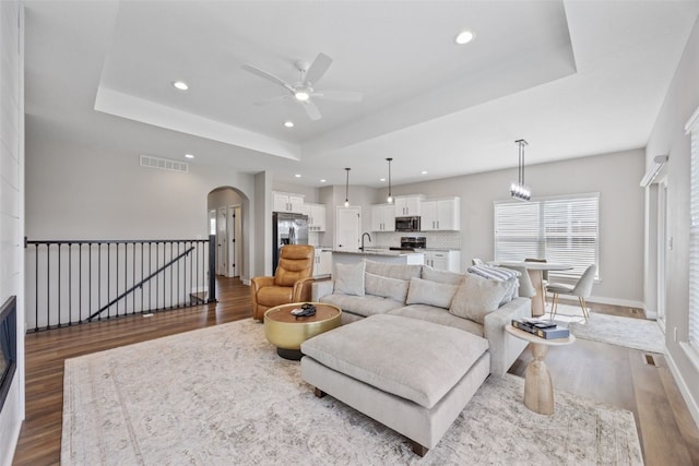 6415 Rookwood Ln, Marion, IA 52302 - living room with arched walkways, wood finished floors, a tray ceiling, a ceiling fan, and recessed lighting
