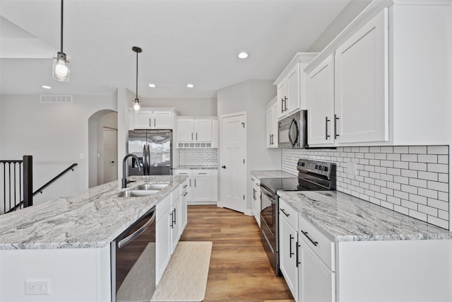 6415 Rookwood Ln, Marion, IA 52302 - kitchen with appliances with stainless steel finishes, arched walkways, a kitchen island with sink, recessed lighting, and white cabinets