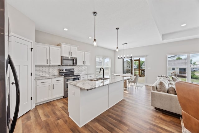 6415 Rookwood Ln, Marion, IA 52302 - kitchen featuring stainless steel appliances, open floor plan, wood finished floors, backsplash, and white cabinetry