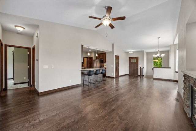 450 2nd St, Fairfax, IA 52228 - living area featuring ceiling fan, a stone fireplace, vaulted ceiling, dark wood-type flooring, and a chandelier