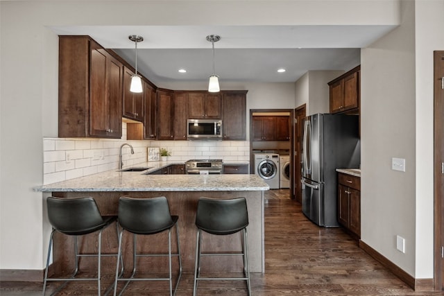 450 2nd St, Fairfax, IA 52228 - kitchen featuring stainless steel appliances, washer and clothes dryer, a peninsula, dark wood-type flooring, and decorative backsplash