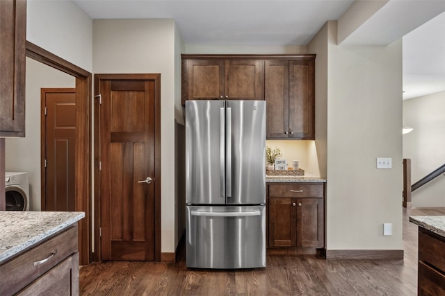 450 2nd St, Fairfax, IA 52228 - kitchen with freestanding refrigerator, washer / clothes dryer, light stone countertops, dark wood-style floors, and dark brown cabinetry