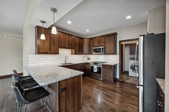 450 2nd St, Fairfax, IA 52228 - kitchen with appliances with stainless steel finishes, a peninsula, washer / dryer, dark wood finished floors, and recessed lighting