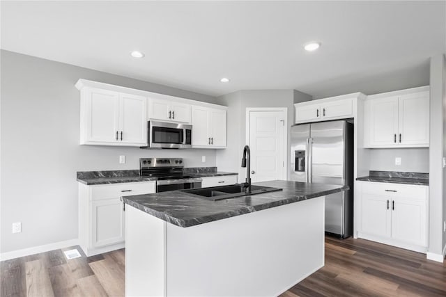 5007 Dostal Dr, Cedar Rapids, IA 52404 - kitchen featuring appliances with stainless steel finishes, dark wood-style floors, white cabinets, a center island with sink, and recessed lighting