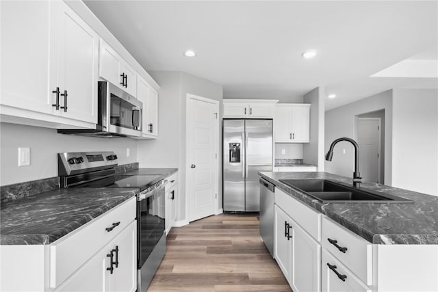5007 Dostal Dr, Cedar Rapids, IA 52404 - kitchen featuring stainless steel appliances, wood finished floors, white cabinets, recessed lighting, and a kitchen island with sink
