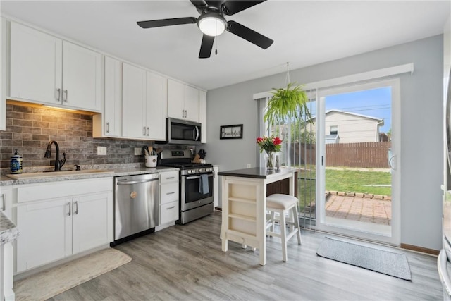 5515 Cedar Dr NW, Cedar Rapids, IA 52405 - kitchen featuring stainless steel appliances, decorative backsplash, light wood finished floors, and white cabinets