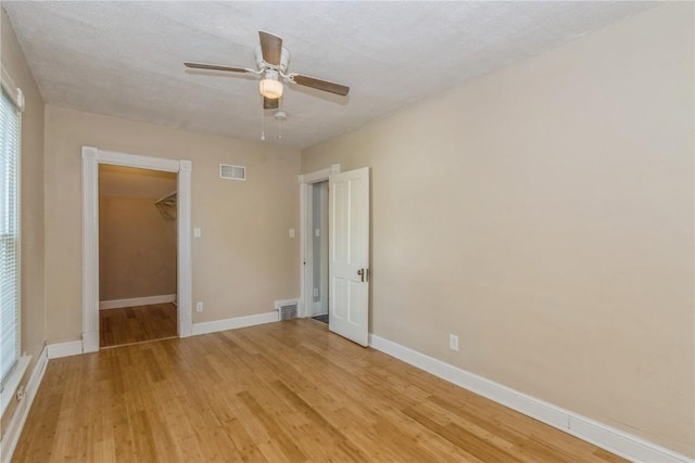 1346 11th St, Marion, IA 52302 - unfurnished bedroom featuring light wood finished floors, a spacious closet, a ceiling fan, and a closet