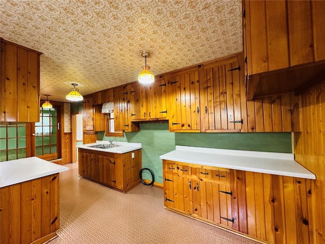 109 Pine St NW, Blairstown, IA 52209 - kitchen with brown cabinets, hanging light fixtures, light countertops, and wooden walls