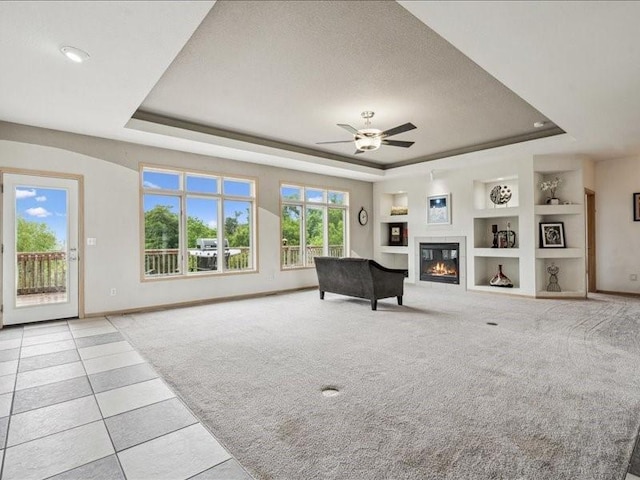 3387 64th St, Palo, IA 52324 - living room with a tray ceiling, built in shelves, light colored carpet, a ceiling fan, and a glass covered fireplace