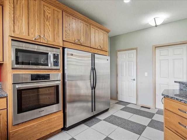 3387 64th St, Palo, IA 52324 - kitchen with appliances with stainless steel finishes, dark stone countertops, and brown cabinetry
