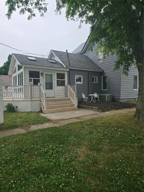 314 Main St, Oxford Junction, IA 52323 - rear view of property featuring a yard, a deck, and a shingled roof