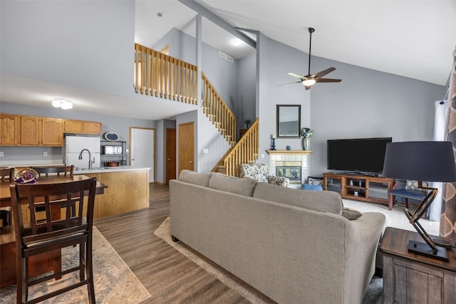 3810 Waterview Ct SW, Cedar Rapids, IA 52404 - living area with high vaulted ceiling, ceiling fan, a glass covered fireplace, dark wood-style flooring, and stairway