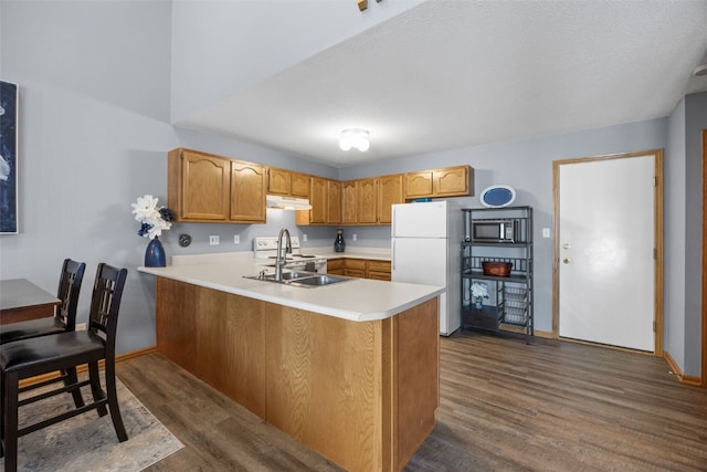 3810 Waterview Ct SW, Cedar Rapids, IA 52404 - kitchen featuring freestanding refrigerator, under cabinet range hood, stainless steel microwave, a peninsula, and dark wood-type flooring