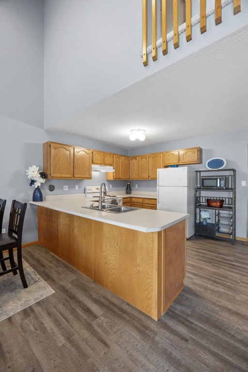 3810 Waterview Ct SW, Cedar Rapids, IA 52404 - kitchen featuring freestanding refrigerator, dark wood finished floors, a peninsula, stainless steel microwave, and light countertops