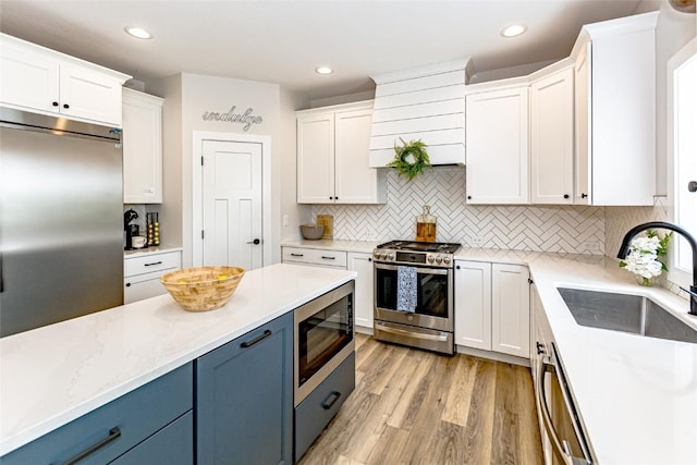 608 Pointer Cir, Center Point, IA 52213 - kitchen with built in appliances, blue cabinetry, white cabinetry, light wood finished floors, and recessed lighting