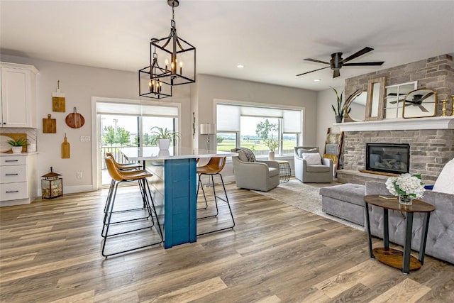 608 Pointer Cir, Center Point, IA 52213 - dining room with a ceiling fan, light wood-style flooring, a large fireplace, a chandelier, and recessed lighting