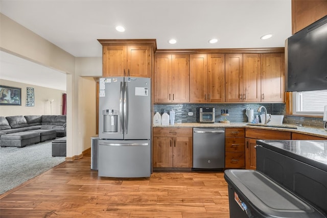 908 18th St SW, Cedar Rapids, IA 52404 - kitchen with appliances with stainless steel finishes, brown cabinetry, backsplash, light stone counters, and recessed lighting