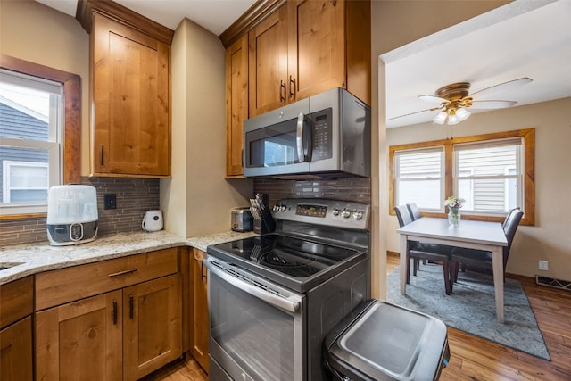 908 18th St SW, Cedar Rapids, IA 52404 - kitchen with stainless steel appliances, backsplash, light wood-style flooring, and light stone countertops