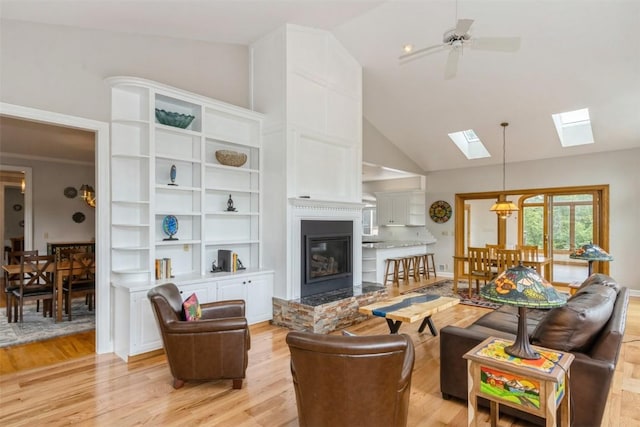 1916 Oak Knoll Ct SE, Cedar Rapids, IA 52403 - living room featuring a skylight, light wood-style flooring, ceiling fan, a glass covered fireplace, and high vaulted ceiling