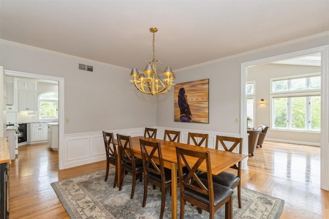 1916 Oak Knoll Ct SE, Cedar Rapids, IA 52403 - dining space featuring a chandelier, crown molding, light wood-type flooring, and a wainscoted wall