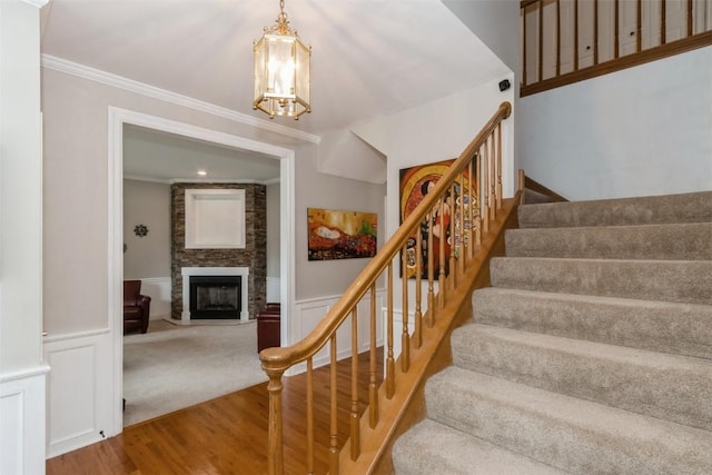 1916 Oak Knoll Ct SE, Cedar Rapids, IA 52403 - stairs featuring a chandelier, a large fireplace, wood finished floors, a wainscoted wall, and a decorative wall