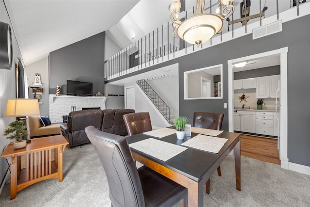 215 40th St Dr SE Unit 301, Cedar Rapids, IA 52403 - dining room with light carpet, high vaulted ceiling, stairway, and a brick fireplace