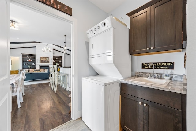 1062 Oak View Ct, Tipton, IA 52772 - laundry area with stacked washer / drying machine, cabinet space, wood finished floors, and a chandelier