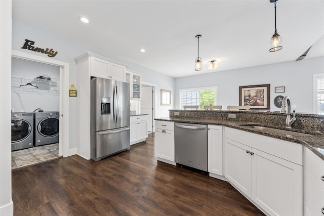 1062 Oak View Ct, Tipton, IA 52772 - kitchen with stainless steel appliances, washing machine and clothes dryer, white cabinetry, decorative light fixtures, and dark stone countertops