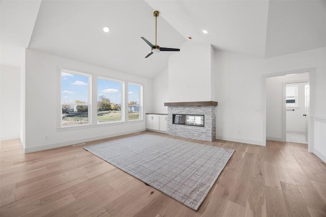 2682 Burr Oak Ct, Marion, IA 52302 - unfurnished living room with high vaulted ceiling, ceiling fan, a stone fireplace, and light wood-style flooring