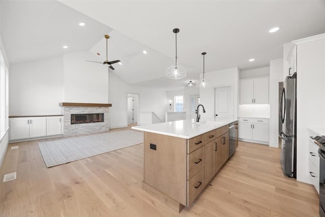 2682 Burr Oak Ct, Marion, IA 52302 - kitchen featuring stainless steel appliances, an island with sink, light wood-style flooring, white cabinetry, and a fireplace