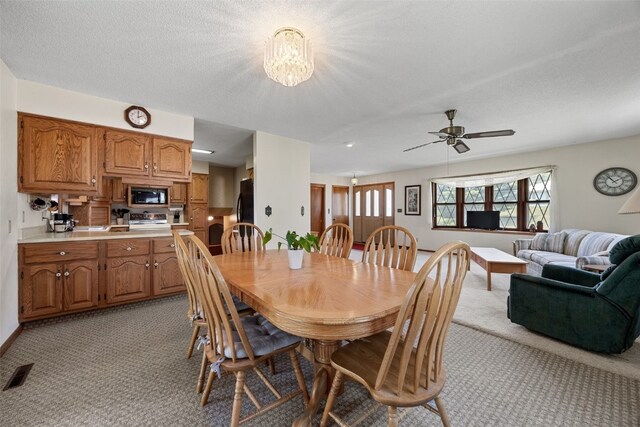 105 Parkview Dr, Tipton, IA 52772 - dining area with light colored carpet, ceiling fan, and a chandelier