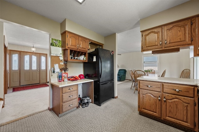 105 Parkview Dr, Tipton, IA 52772 - kitchen featuring freestanding refrigerator, light carpet, brown cabinetry, plenty of natural light, and a textured ceiling