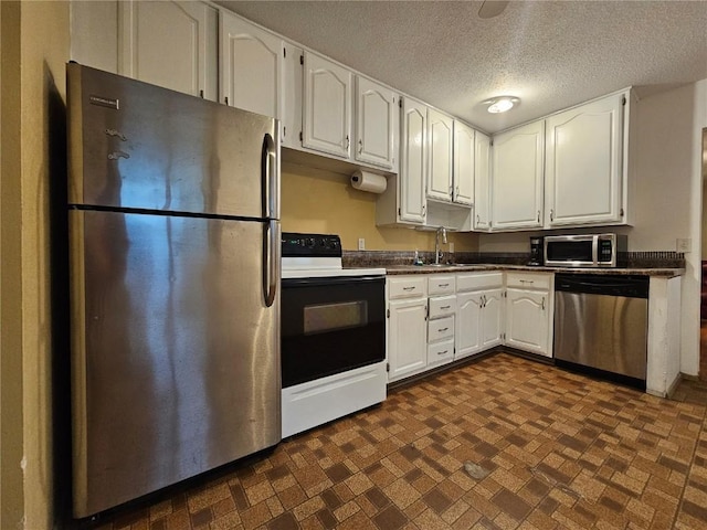 1523 Golden Valley Dr, Bettendorf, IA 52722 - kitchen featuring appliances with stainless steel finishes, dark countertops, white cabinetry, brick patterned floors, and a textured ceiling