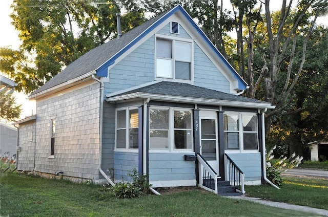 1402 N St SW, Cedar Rapids, IA 52404 - view of front facade featuring a shingled roof, entry steps, a front lawn, and a sunroom