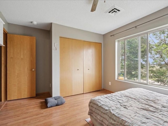 1020 240th St NE Unit 8, North Liberty, IA 52317 - bedroom featuring wood finished floors, a textured ceiling, a closet, and a ceiling fan