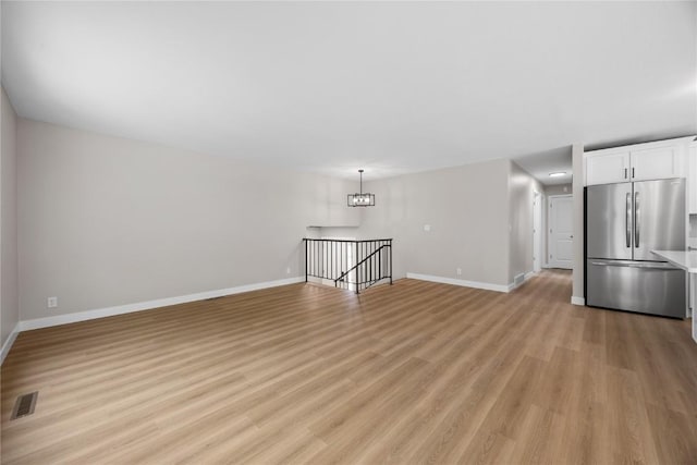 6612 Boulder Dr, Cedar Rapids, IA 52405 - unfurnished living room featuring light wood finished floors and a chandelier