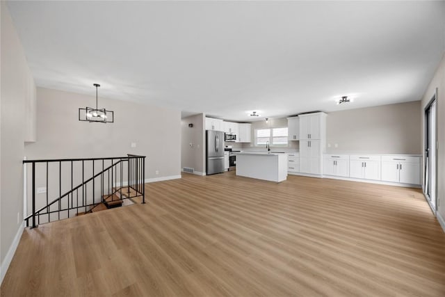 6612 Boulder Dr, Cedar Rapids, IA 52405 - unfurnished living room featuring light wood finished floors and a chandelier