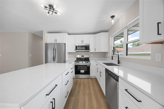 6612 Boulder Dr, Cedar Rapids, IA 52405 - kitchen with appliances with stainless steel finishes, light countertops, light wood-type flooring, white cabinetry, and a center island