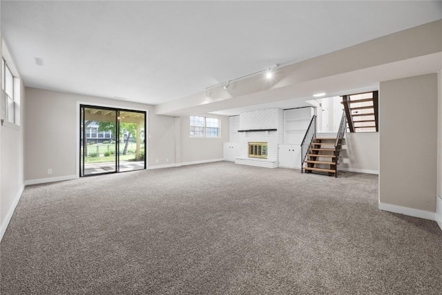 6612 Boulder Dr, Cedar Rapids, IA 52405 - unfurnished living room featuring rail lighting, carpet floors, stairway, and a brick fireplace