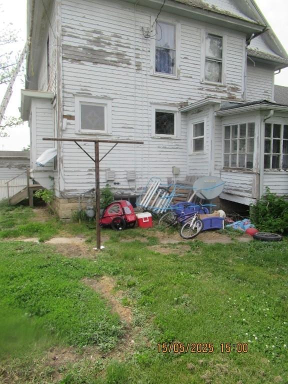 606 Meridian St, Tipton, IA 52772 - rear view of house featuring a yard and a sunroom