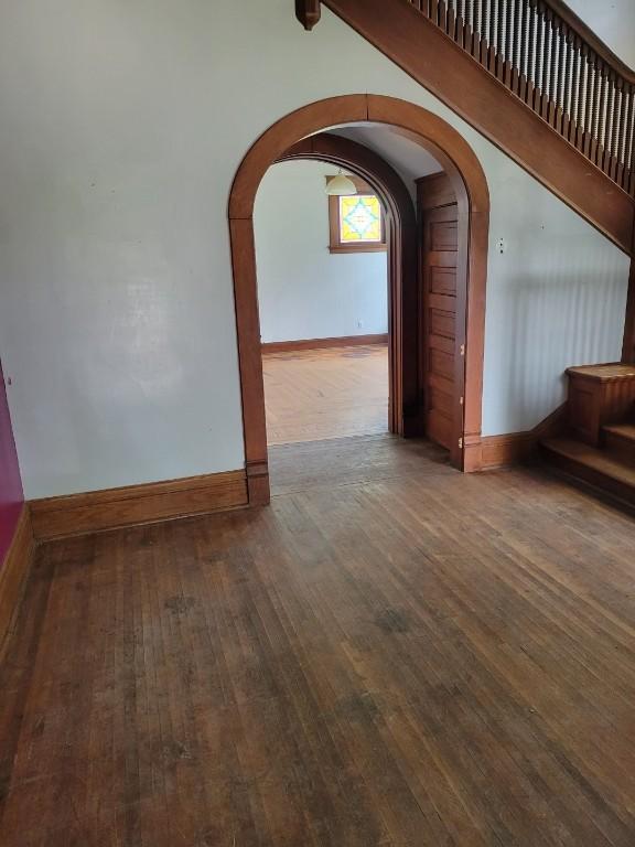 606 Meridian St, Tipton, IA 52772 - unfurnished living room with hardwood / wood-style flooring, arched walkways, and stairs