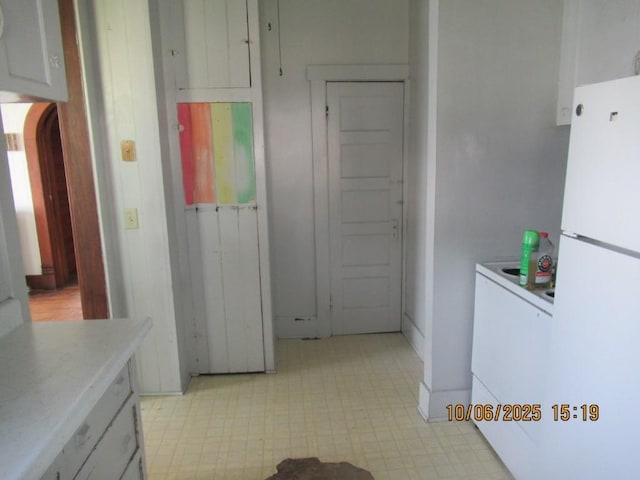 606 Meridian St, Tipton, IA 52772 - kitchen with freestanding refrigerator, light floors, light countertops, and arched walkways
